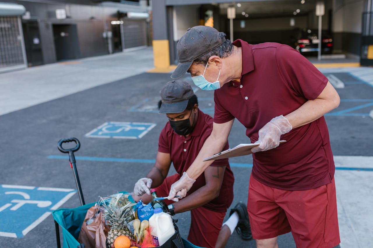 Delivery workers in masks and gloves organizing groceries outdoors, ensuring safety.