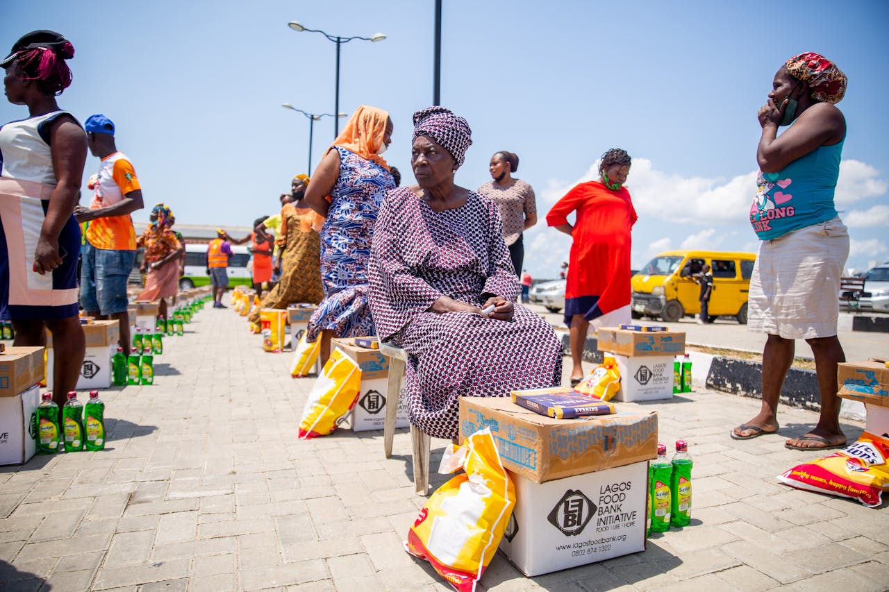 A group of women receiving aid packages from Lagos Food Bank on a sunny day.
